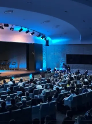 Gran auditorio de convenciones corporativas con escenario de Innovation Summit e iluminación azul.