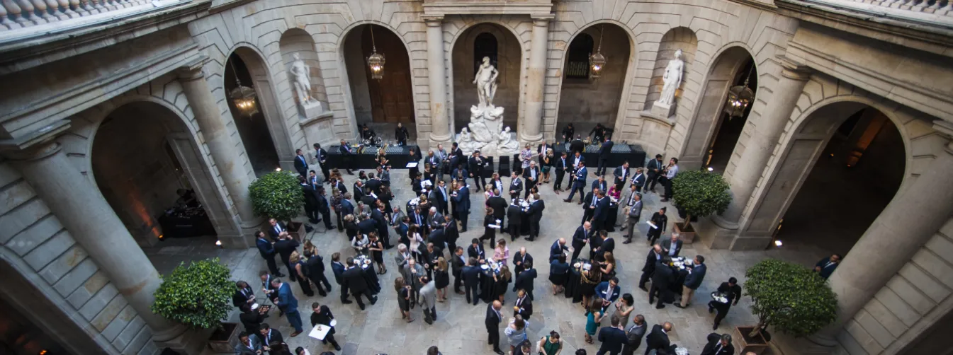 Interior view of the historic Casa Llotja de Mar in Barcelona, highlighting the majestic Gothic stone arches and high ceilings of the medieval trading hall, elegantly set up for a luxury gala or exclusive business function.