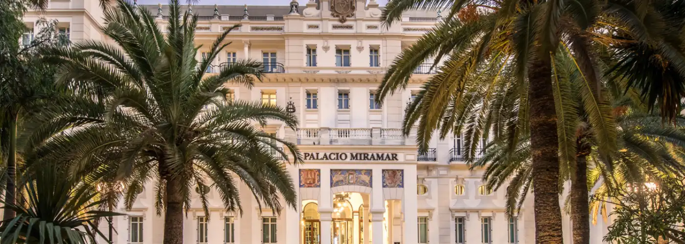 Elegant historic facade of Gran Hotel Miramar in Malaga surrounded by palm trees