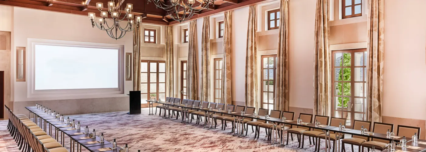 Elegant luxury conference room in Mallorca hotel with U-shaped table chandeliers wooden beams and large projection screen