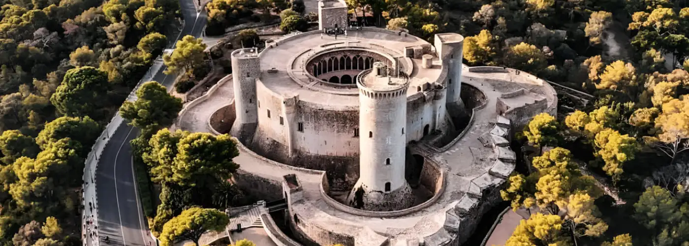 Aerial view of iconic circular Bellver Castle in Palma de Mallorca surrounded by lush green forest