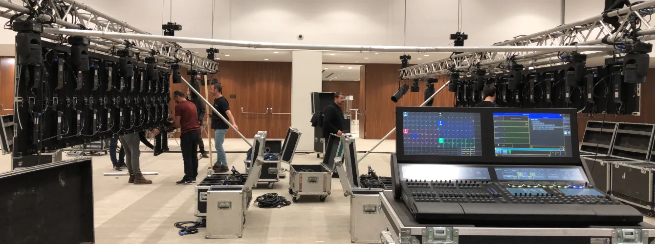 Technical team assembling large LED screen panels next to a professional lighting and video control desk.