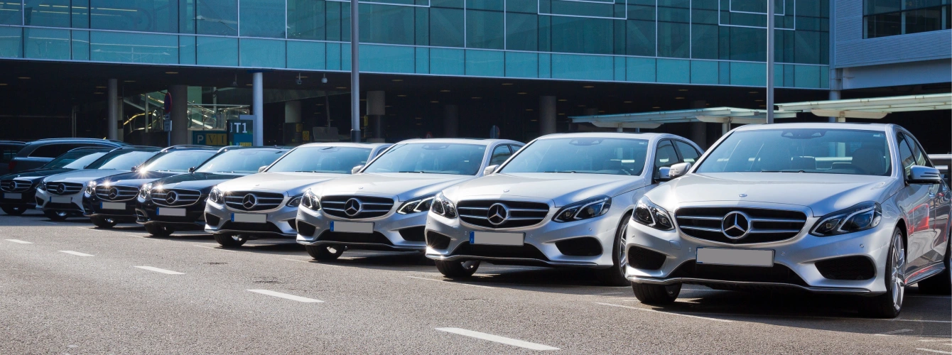 A line of white BMW sedans with "Guest Shuttle" branding for corporate event transportation services.