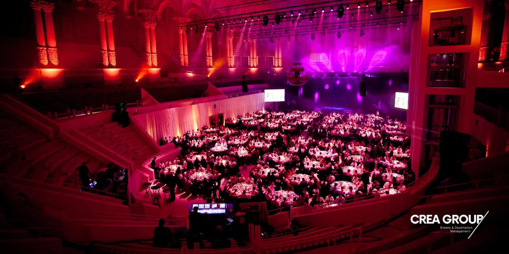 Grand dîner de gala d'entreprise et voyage d'évènementiel dans un lieu emblématique de Barcelone éclairé en tons magenta.