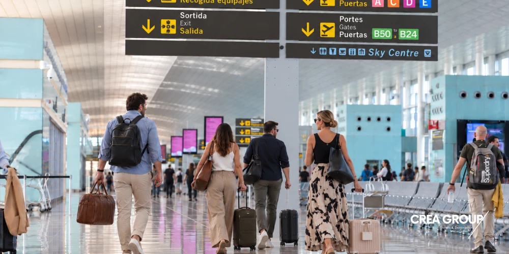 Grup de viatgers caminant amb equipatge per la terminal de l'aeroport Barcelona-El Prat seguint els senyals cap a les portes d'embarcament.